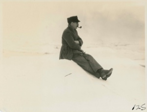 Image of Man with pipe sitting on snow bank